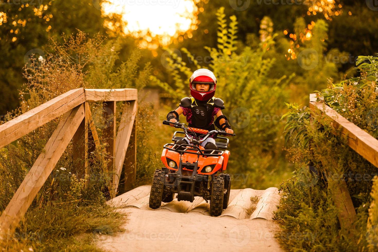 Lycklig liten flicka spelar på väg på de dag tid. han körning på quad cykel i de parkera. barn har roligt på de natur. begrepp av lycka. foto