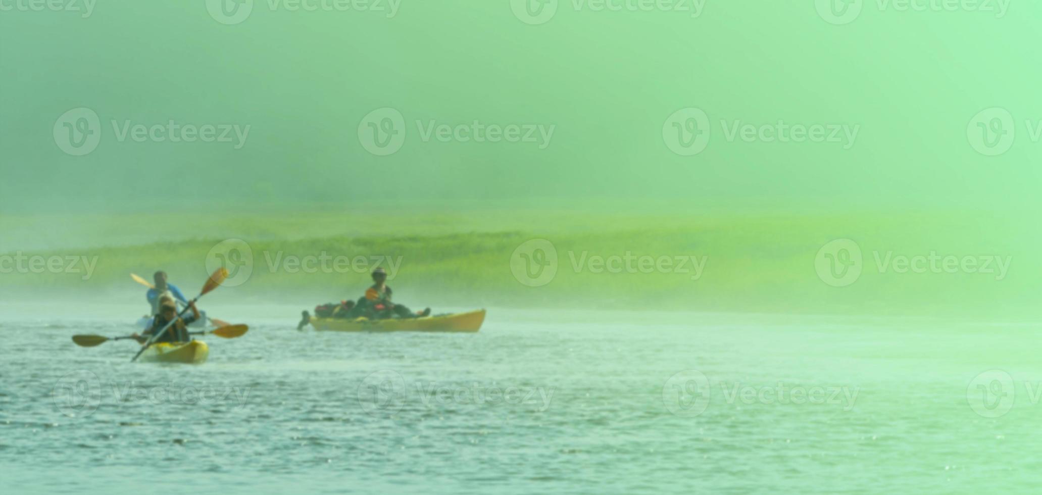 få människor på kajaker resa tvärs över de sjö i en dimmig morgon- foto