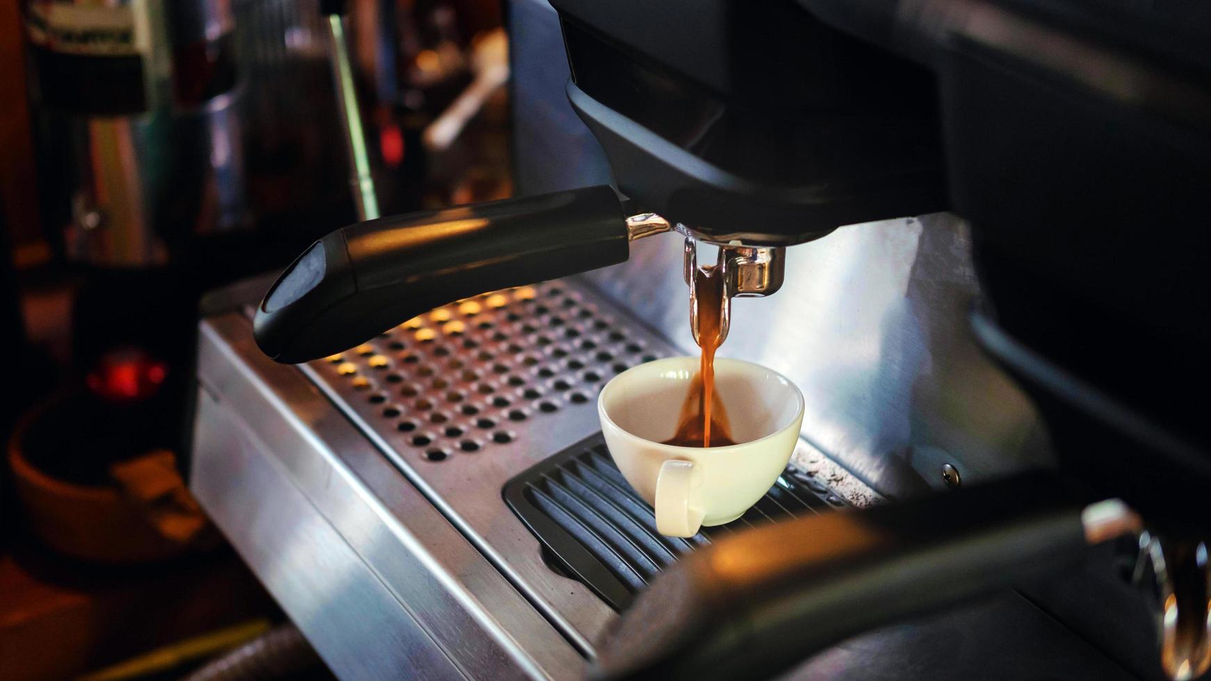 kaffe kopp av espresso häller från de kaffe maskin. professionell kaffe bryggning i de Kafé foto