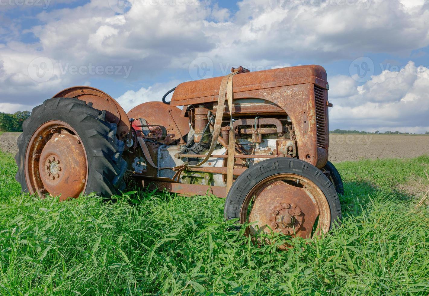 övergiven gammal och rostig traktor på fält, norr frisia, tyskland foto