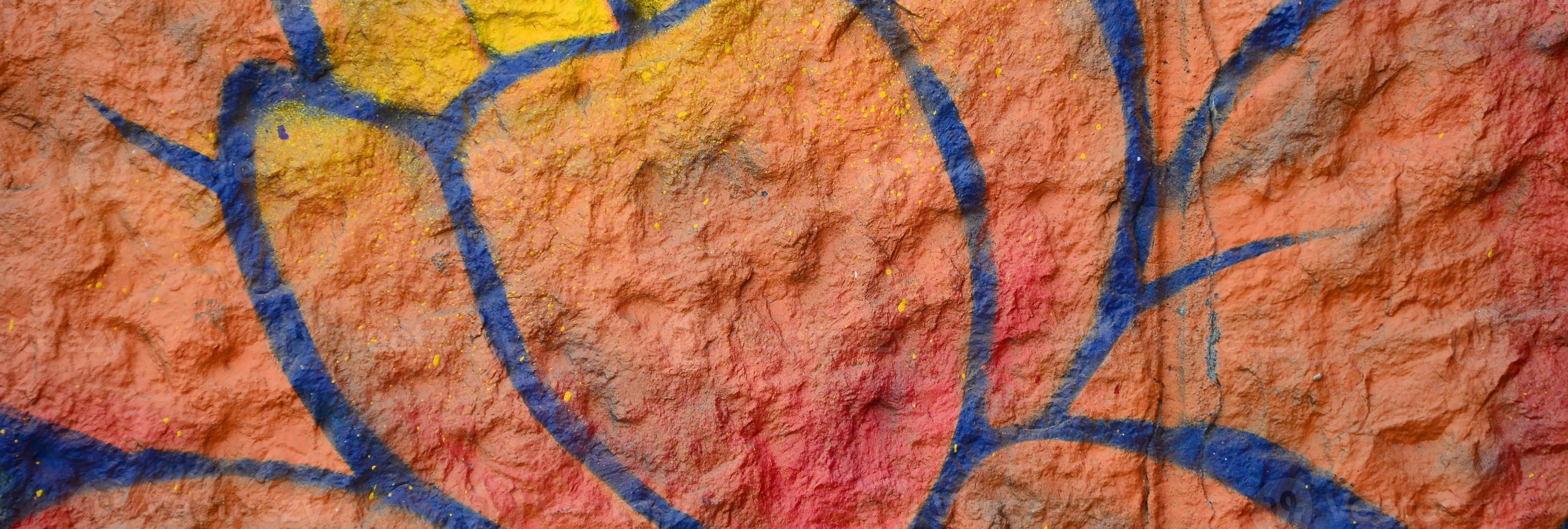 fragment av graffiti ritningar. de gammal vägg dekorerad med måla fläckar i de stil av gata konst kultur. orange blomma foto