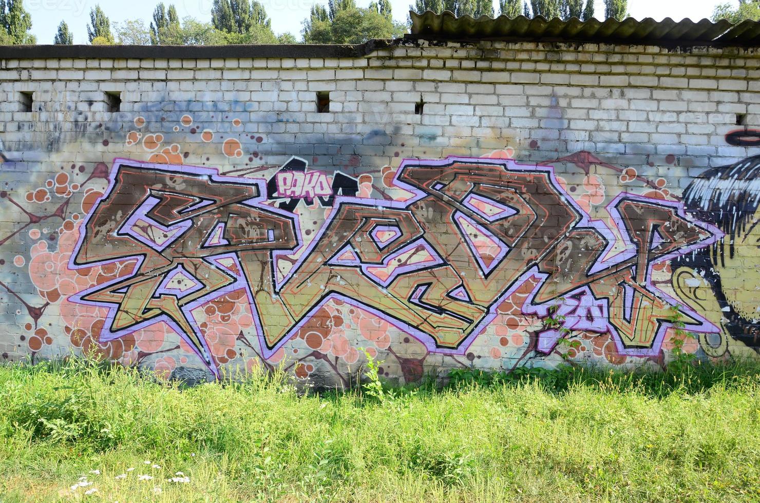 fragment av graffiti ritningar. de gammal vägg dekorerad med måla fläckar i de stil av gata konst kultur. färgad bakgrund textur i värma toner foto