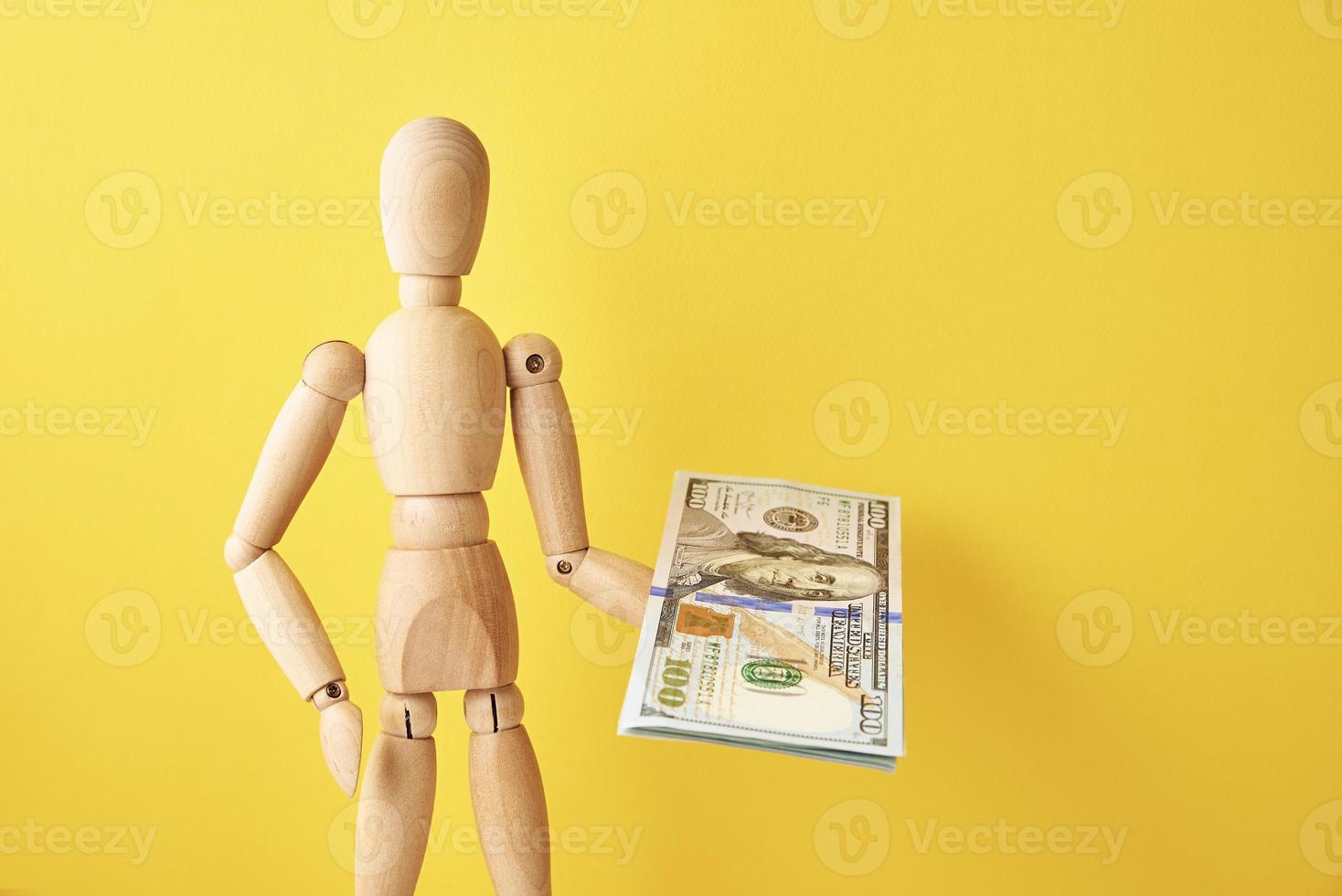 trä- docka på gul bakgrund med dollar pengar foto