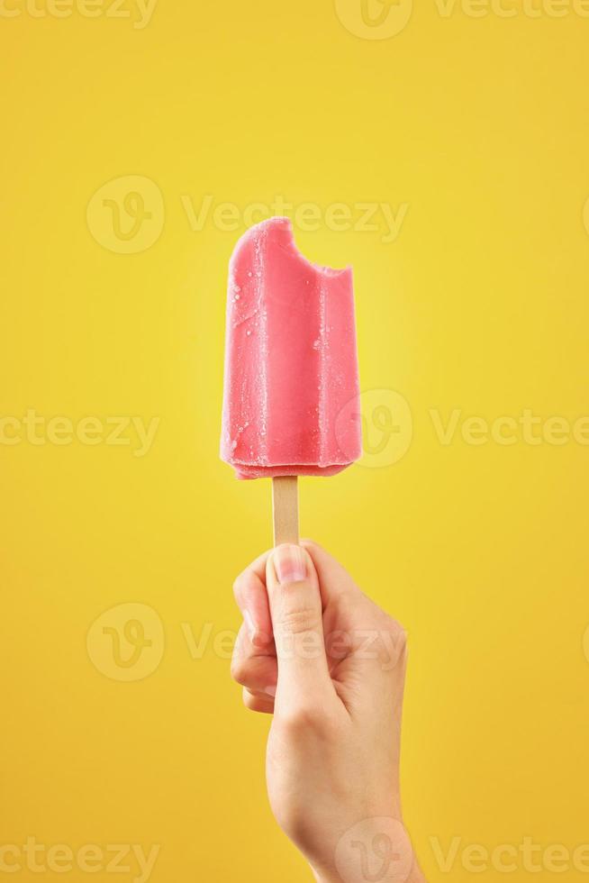 Bitten röd frysta frukt is grädde isglass på gul bakgrund foto