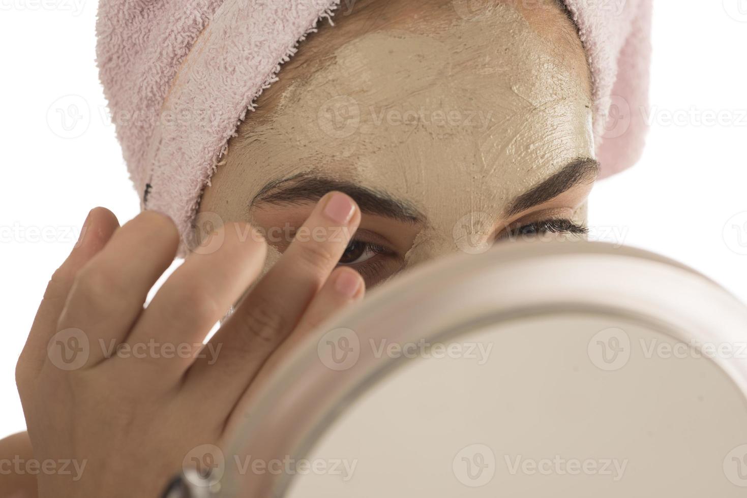 skönhet förfaranden hud vård begrepp. ung kvinna applicering ansiktsbehandling lera lera mask till henne ansikte foto