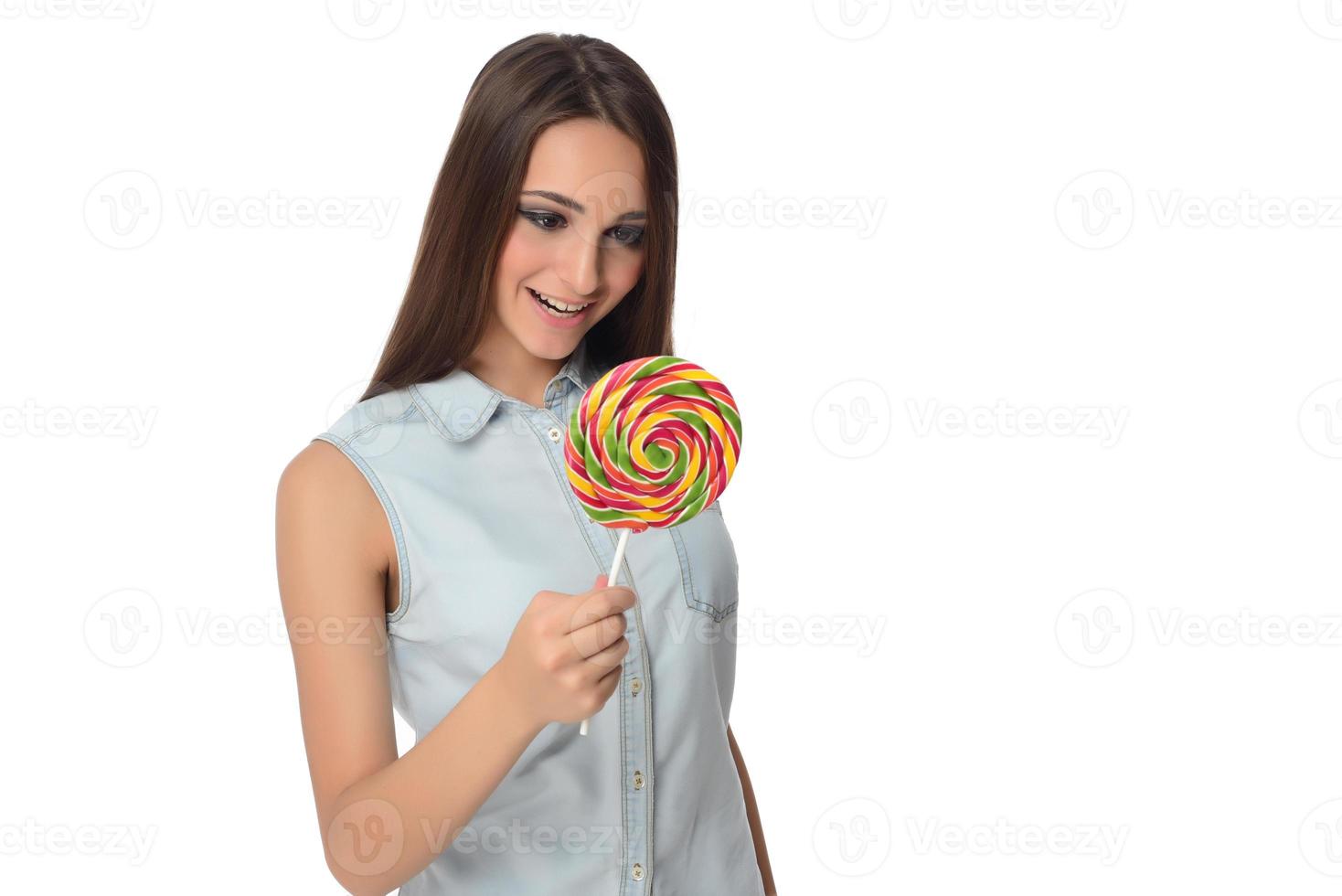 kvinna slick ljuv godis. kvinna modell äter utsökt konfektyr klubba med överraskad uttryck. studio skott isolerat vit bakgrund foto