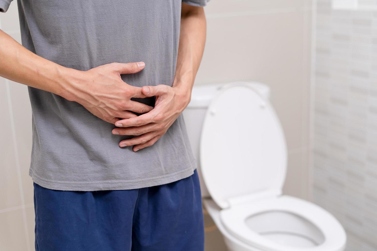 man stående har diarre och allvarligt toxisk mat. man Rör mage i de badrum. abdominal smärta, diarre, kolon cancer begrepp foto