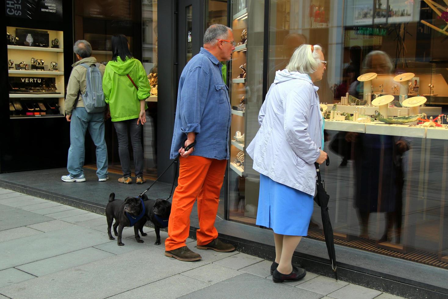 Wien, österrike - september 03, 2014. par av två äldre människor med två hundar ser på en affär fönster av Smycken affär. foto