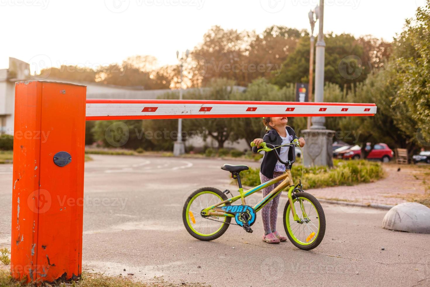 liten flicka på en cykel cykel nära de barriär foto