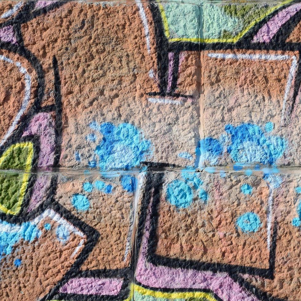 fragment av graffiti ritningar. de gammal vägg dekorerad med måla fläckar i de stil av gata konst kultur. färgad bakgrund textur i värma toner foto