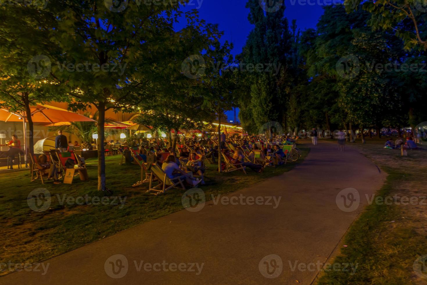 öppen luft ölträdgård på Strand av flod spree under kväll skymning i sommar foto