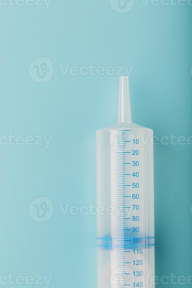 en stor medicinsk spruta på en blå bakgrund med en skala, en kopia av de Plats. de begrepp av minimalism. foto