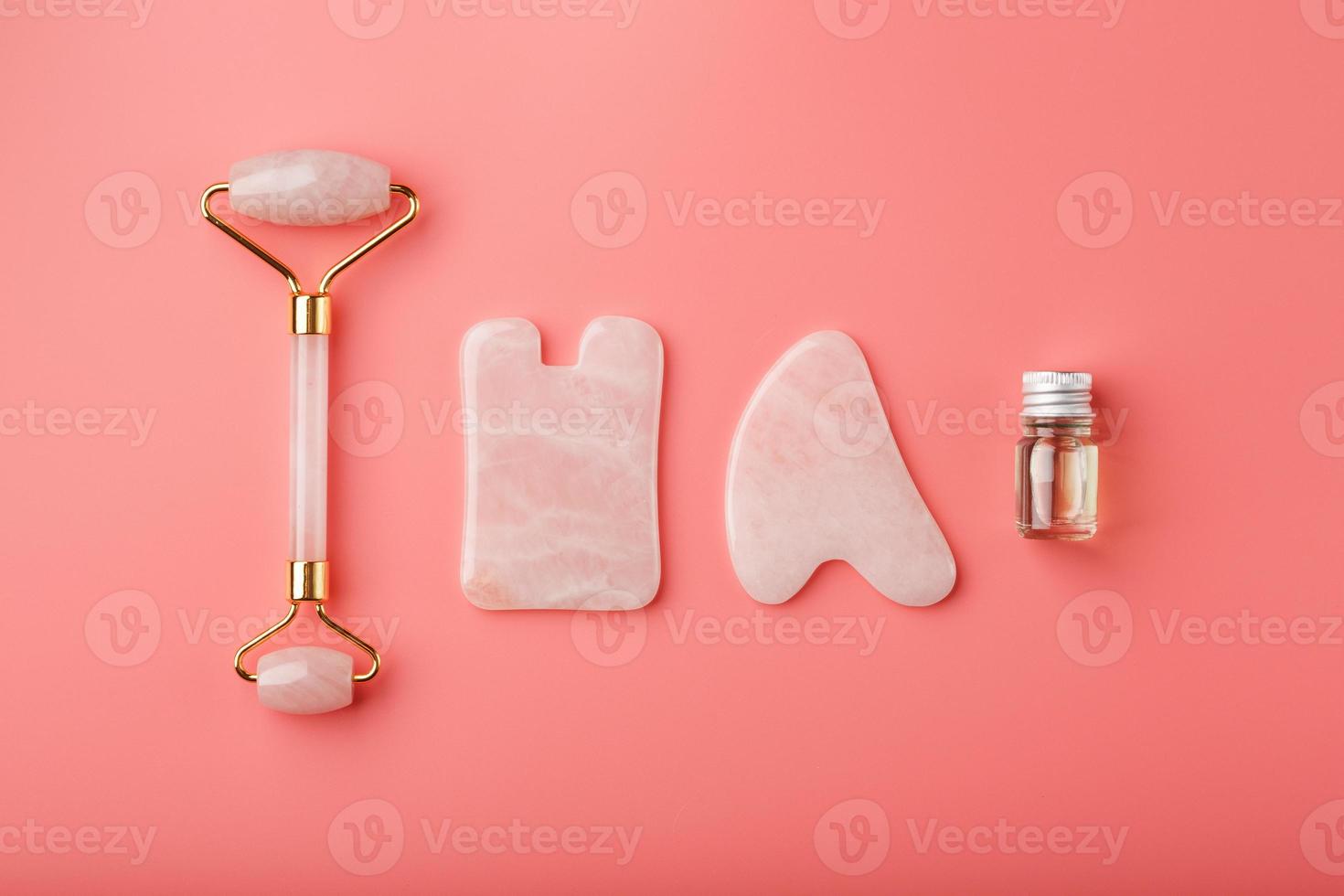 en uppsättning av verktyg för ansikte massage Metod gua sha tillverkad av naturlig reste sig kvarts på en rosa bakgrund. vält, jade sten och olja i en glas burk för ansikte och kropp vård. foto