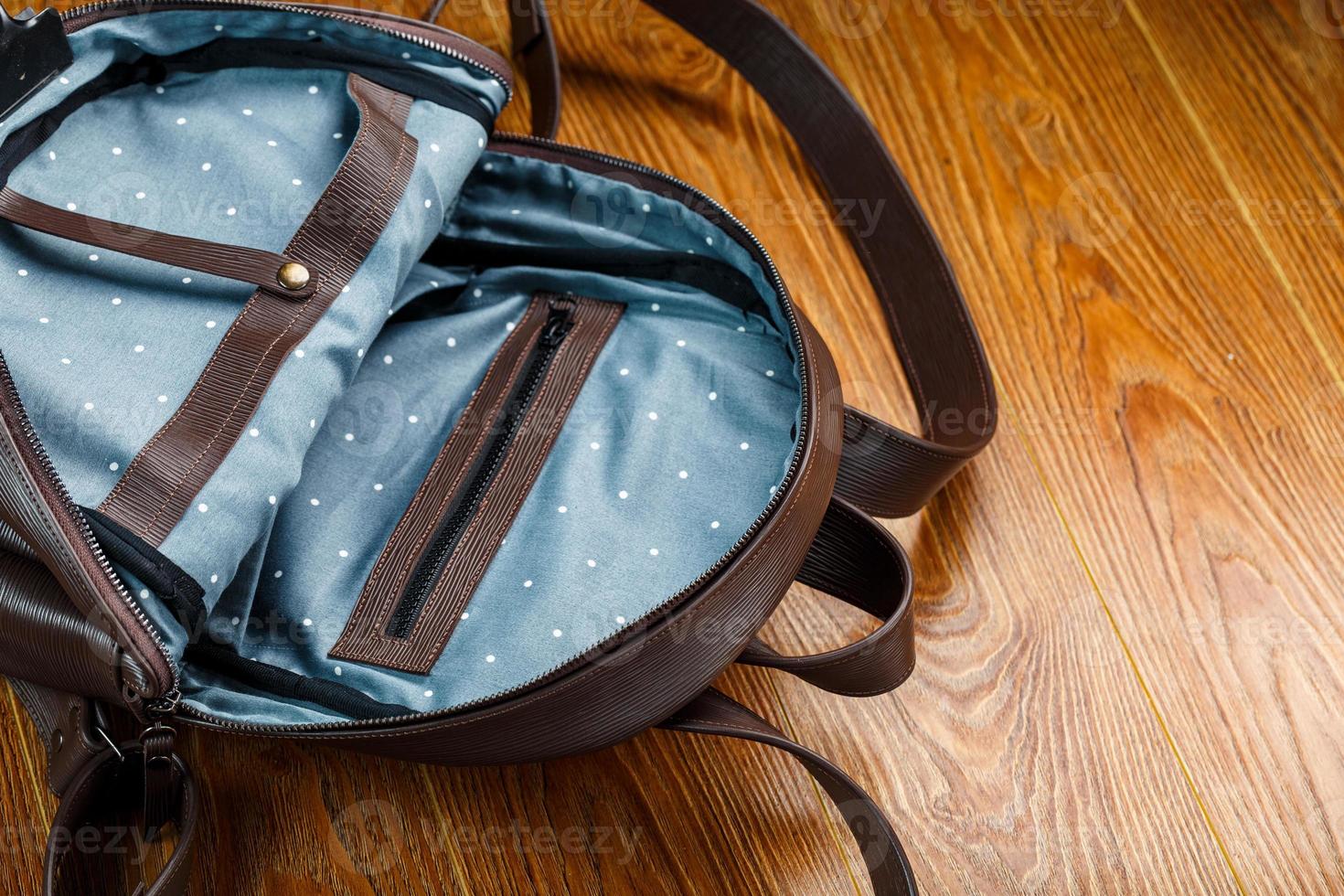 öppen tömma väska tillverkad av handgjort äkta läder med element av lås på en trä- bakgrund. foto