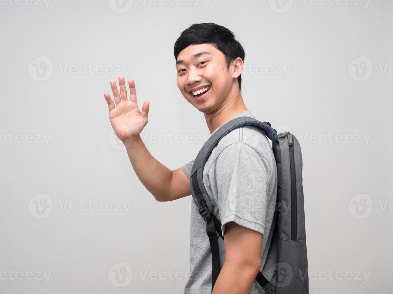 asiatisk man med ryggsäck leende sväng runt om till säga Hej isolerat foto