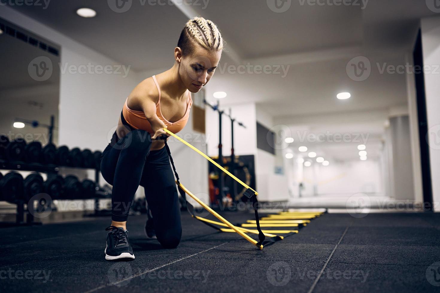 Inaktiverad atletisk kvinna använder sig av fötter rörlighet stege under sporter Träning i en Gym. foto