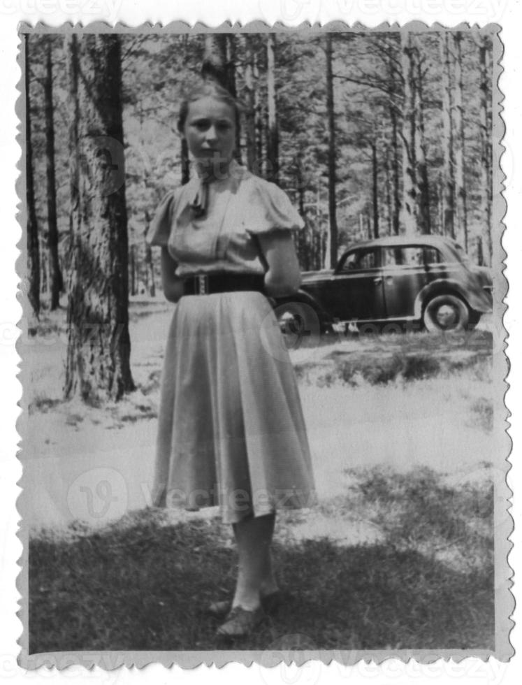 en ung flicka i de skog mot de bakgrund av en moskvich bil. Foto tagen i 1955.