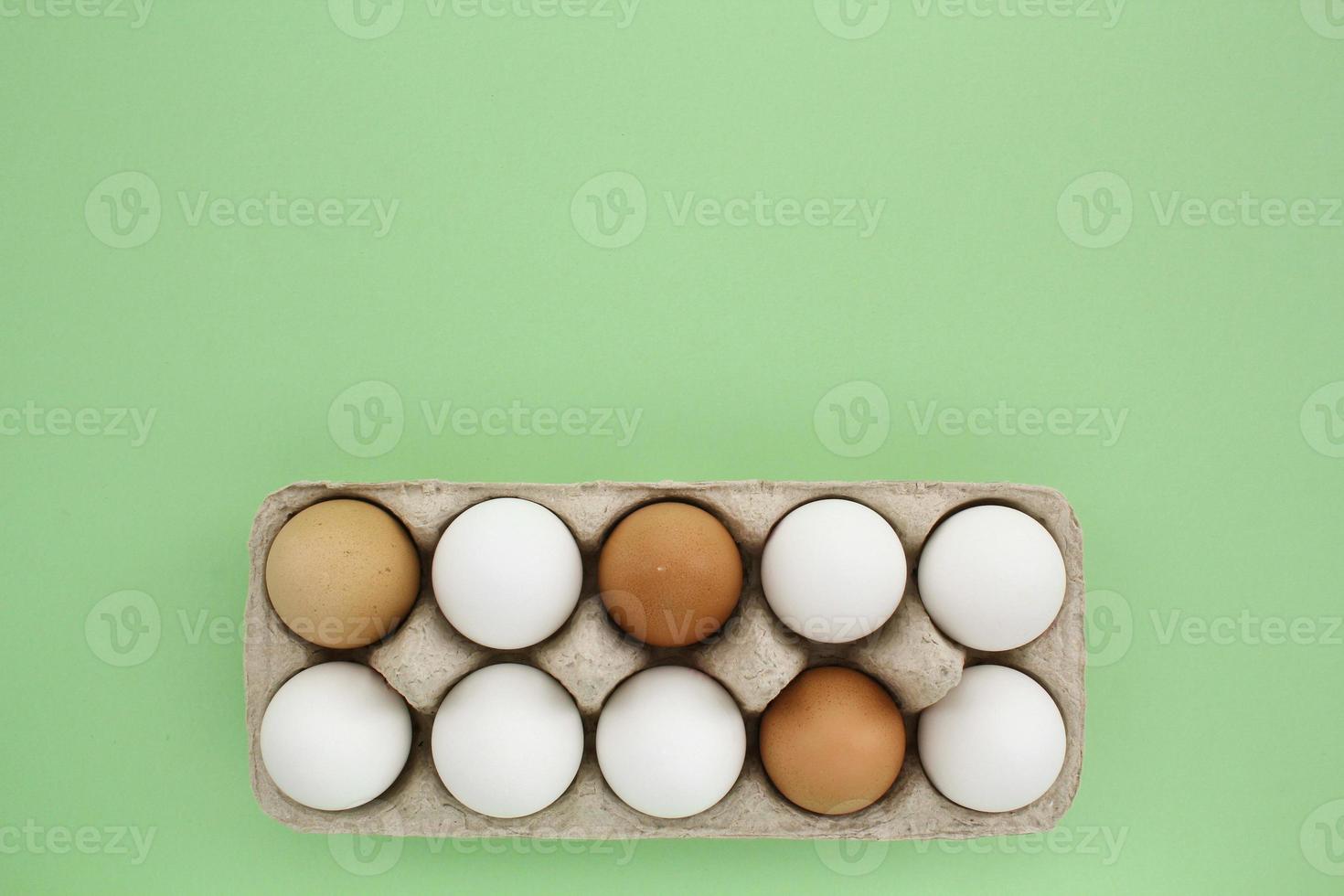 färsk vit och brun kyckling ägg i kartong papper låda på grön bakgrund. naturlig friska näring organisk bruka mat produkt begrepp. värld ägg dag, påsk Semester sammansättning. kopia Plats, flatlay foto