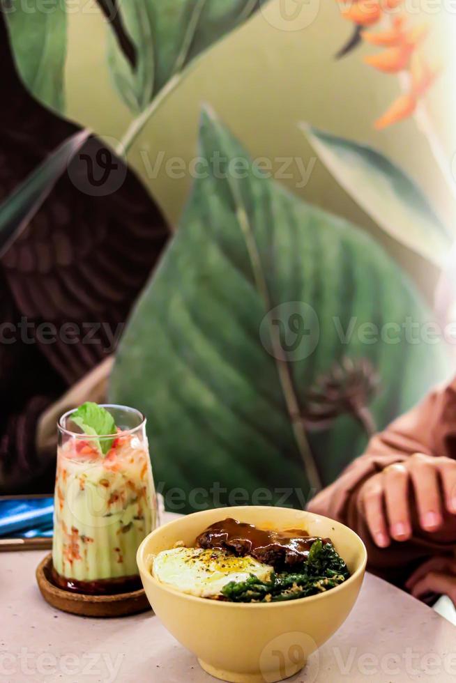 en glas av avokado juice med is och kokt spaghetti fylld med ägg och grönsaker foto
