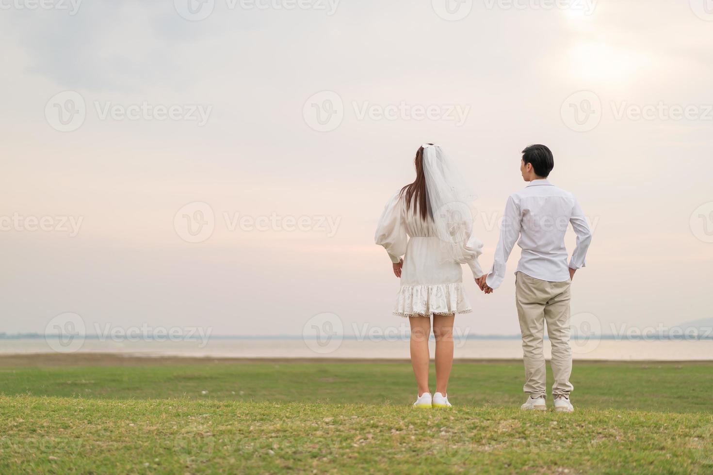 lyckliga unga asiatiska par i brud och brudgum kläder foto