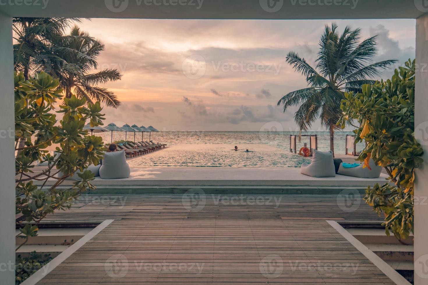 lyx utomhus- vid poolen, oändlighet simning slå samman med handflatan träd och solnedgång himmel stänga till strand och hav. skön tillflykt strand slå samman, lugn familj eller par sommar semester destination foto