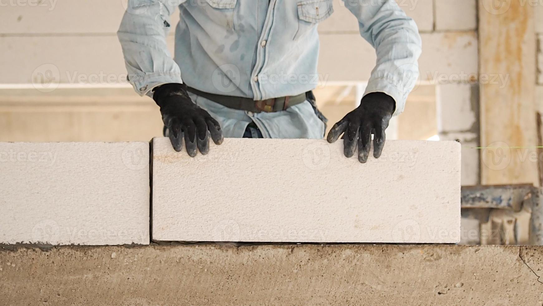 konstruktion arbetare är framställning vit lättvikt betong block den där är bättre än cement tegelstenar, populär i de konstruktion av hem och offentlig byggnader. foto