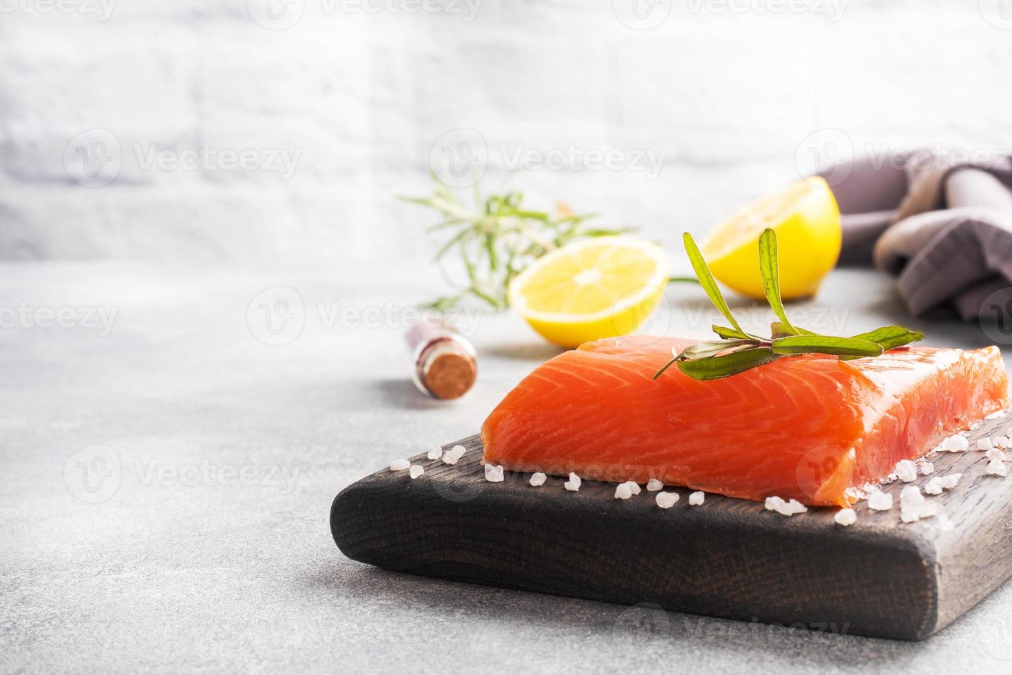 laxfilé, röd saltad fisk på en trä skärbräda. citron, rosmarin kryddor. kopieringsutrymme. foto