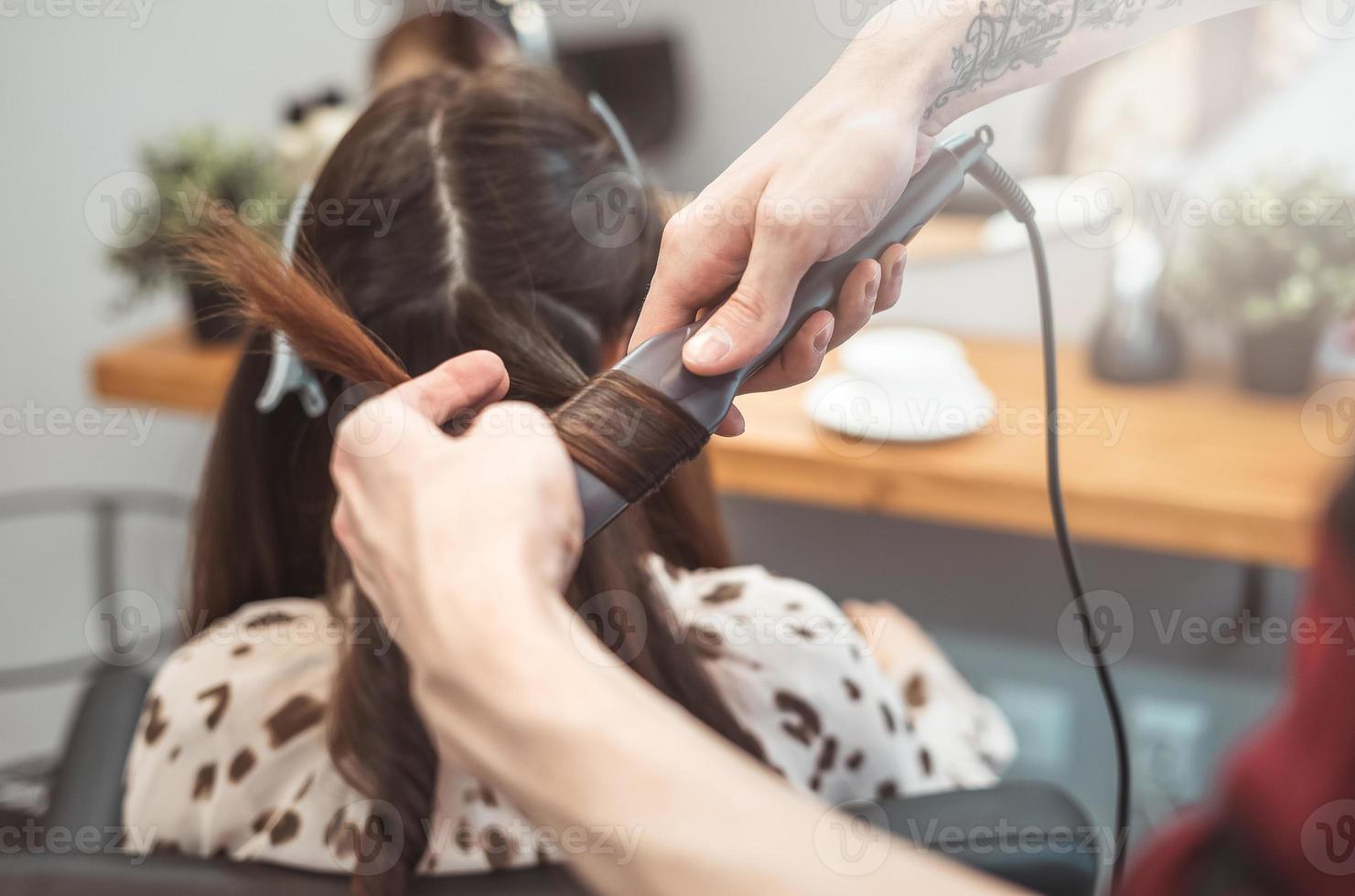 hår frisör barberare styling lång hår med hår järn för skön ung kvinna i skönhet salong arbetssätt ögonblick foto