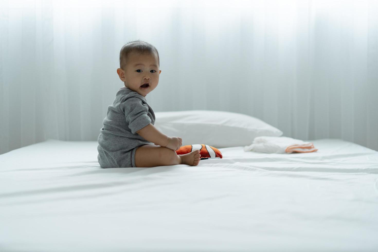 asiatisk bebis spelar leksaker och trä- pussel på de säng. bebis är Lycklig till vara tillsammans. aktiviteter till främja de utveckling av de bebis ålder. foto