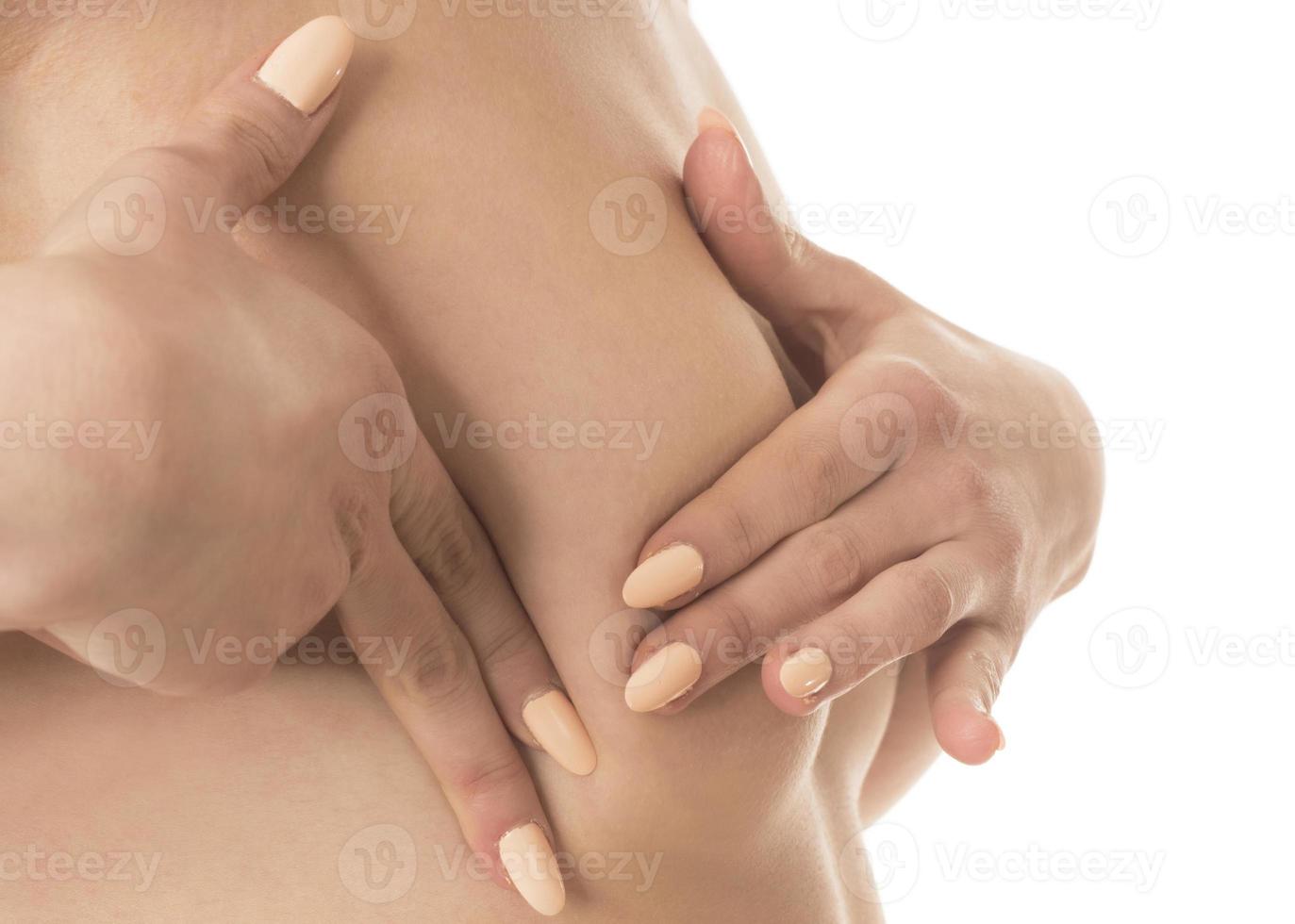 kvinna hand kontroll klumpar på henne bröst för tecken av bröst cancer foto
