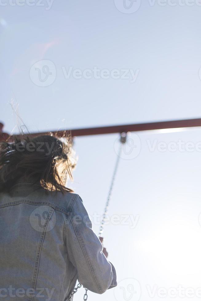 ett infantil och Lycklig kvinna Sammanträde på en unge glida på en lekplats foto