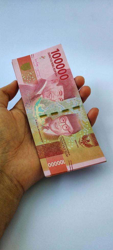 porträtt av indonesiska sedlar rp. 100 000 i hand. indonesiska rupiah valuta isolerat på vit bakgrund foto