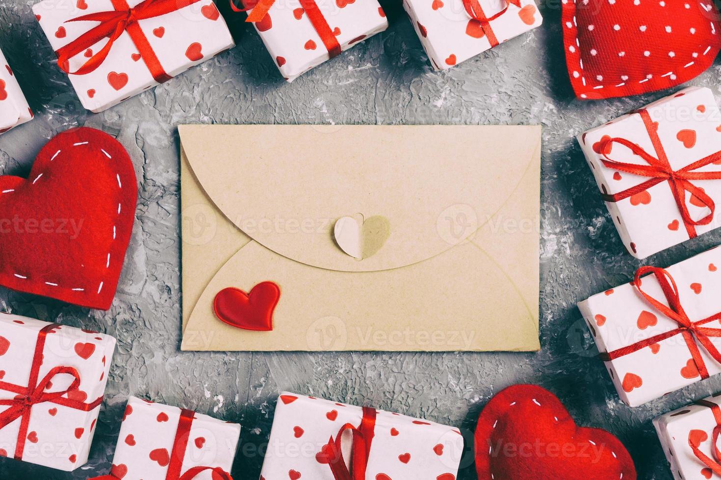 kuvert post med röd hjärta och gåva låda över grå cement bakgrund. valentine dag kort, kärlek eller bröllop hälsning begrepp foto