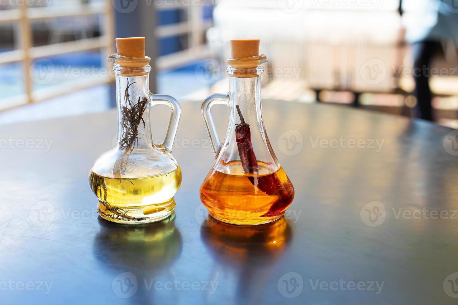 på de tabell är två glas flaskor fylld med kryddad och rosmarin oliv olja. närbild. Smör för pizza, resten i ett italiensk restaurang. foto