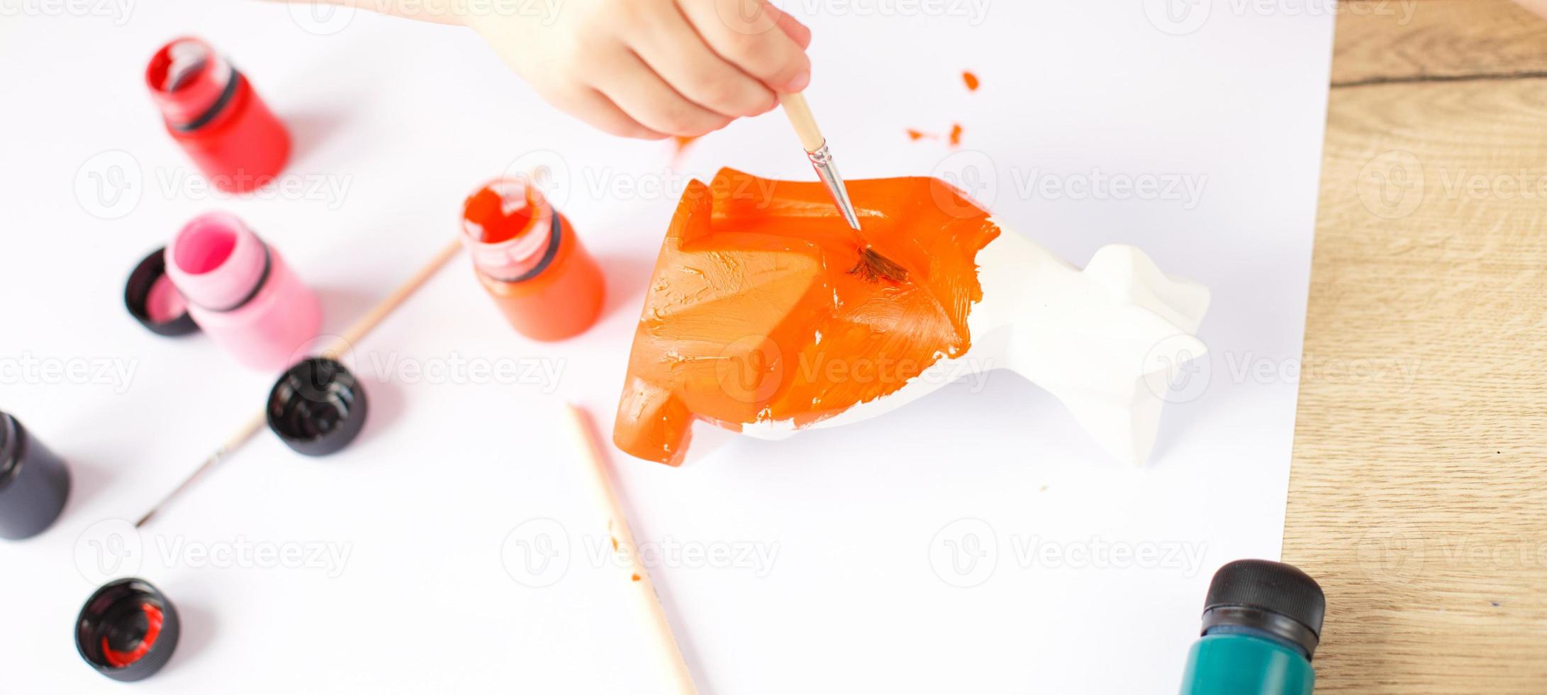en liten flicka målarfärger en leksak räv tillverkad av lera. diy begrepp foto