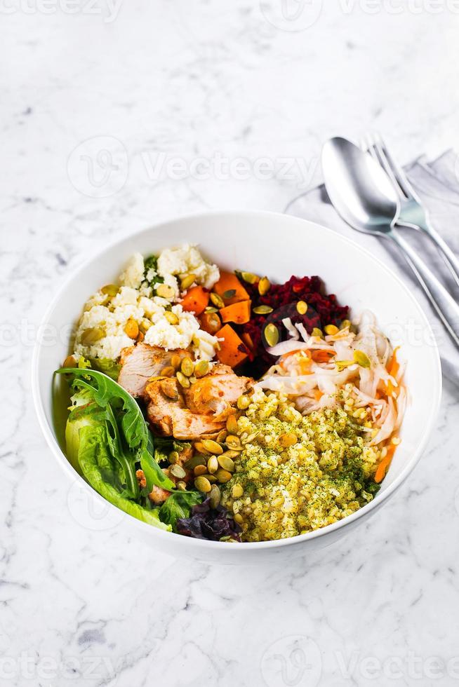 friska lunch skål. sallad med kött, ost, bulgur och grönsaker på marmor bakgrund. kopia Plats foto