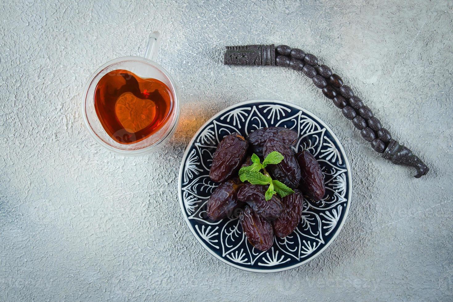 ramadan mat begrepp. färsk datum, rosenkrans pärlor, kopp av te på betong bakgrund. ramadan kareem foto