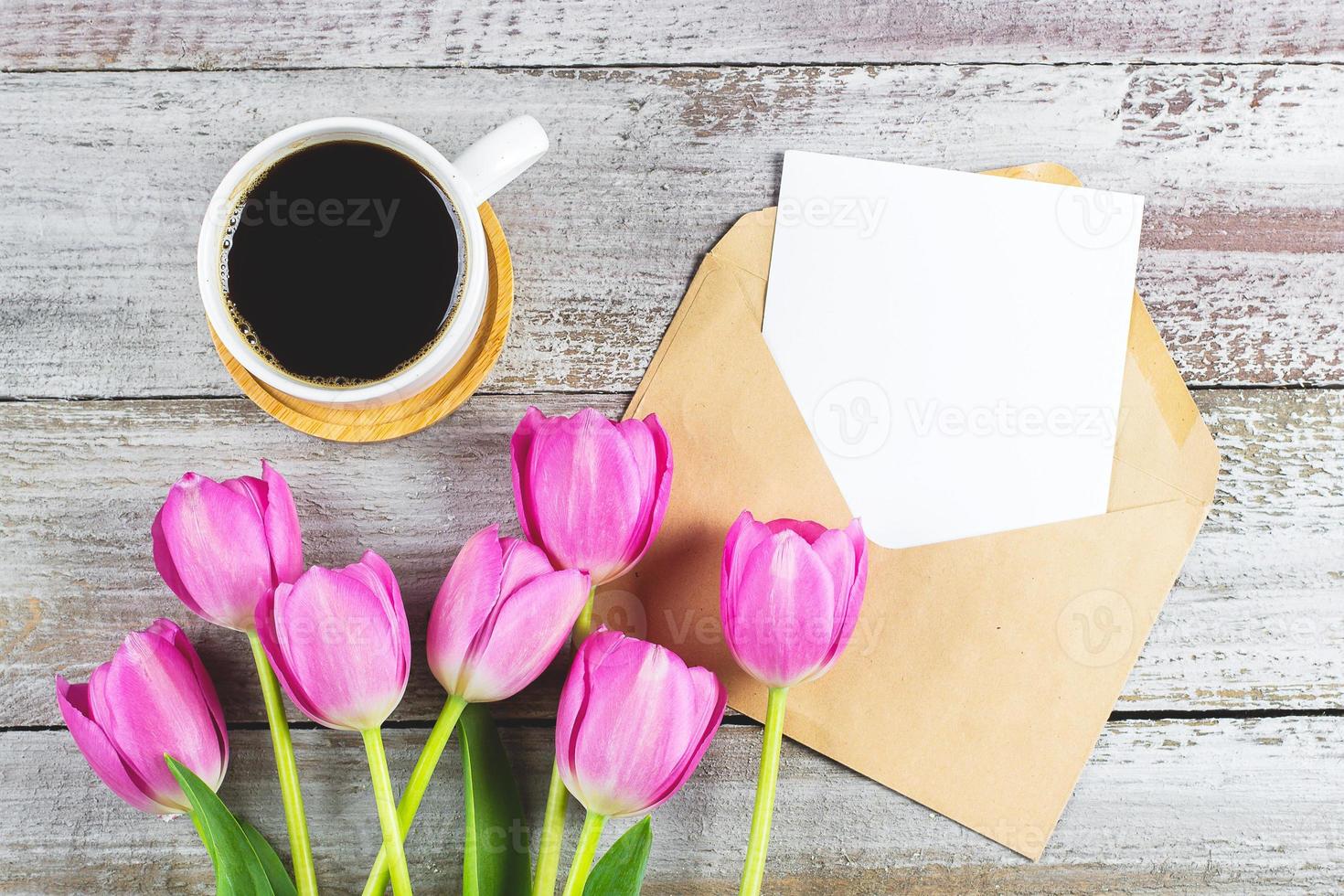 mors dag bakgrund. vår rosa tulpaner blommor, kopp av kaffe och tömma kort på sjaskig trä- bakgrund. hälsning kort för kvinnor eller mödrar dag. platt lägga, topp se, kopia Plats. attrapp begrepp. foto