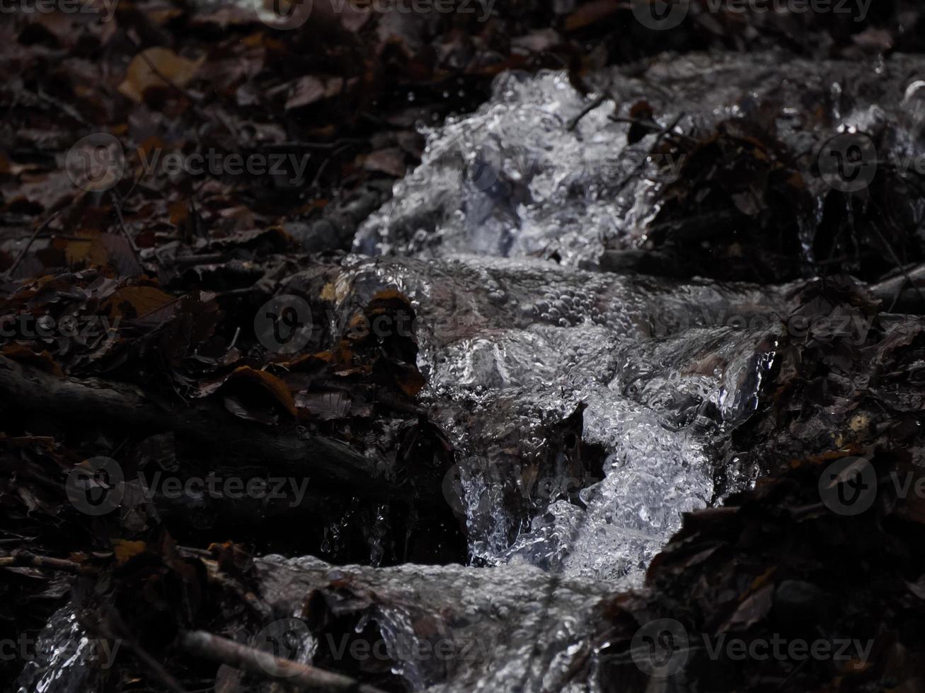 små strömmande flod på grund av till snö smälta formning en rena kaskad med färsk Häftigt vatten omgiven förbi vegetation berg foto