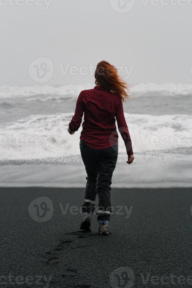 kvinna gående längs reynisfjara strand naturskön fotografi foto