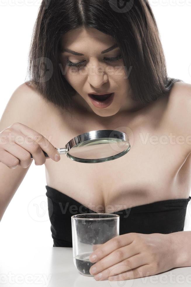 attraktiv kvinna ser i de glas av vatten med förstorande glas. isolerat foto