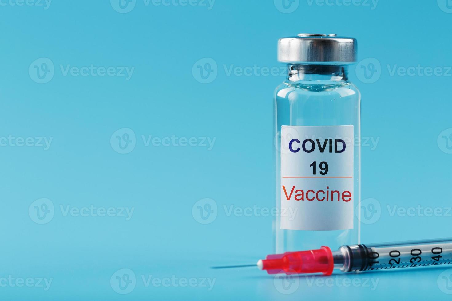 spruta och ampull med en vaccin mot de covid-19 virus mot sjukdomar på en blå bakgrund. foto