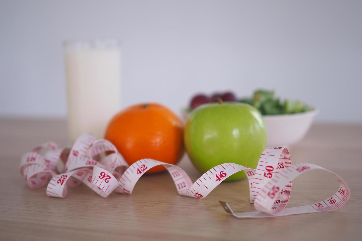 fokus på mätning tejp - friska mat med vegetabiliska sallad, orange, äpple och mjölk. begrepp diet foto