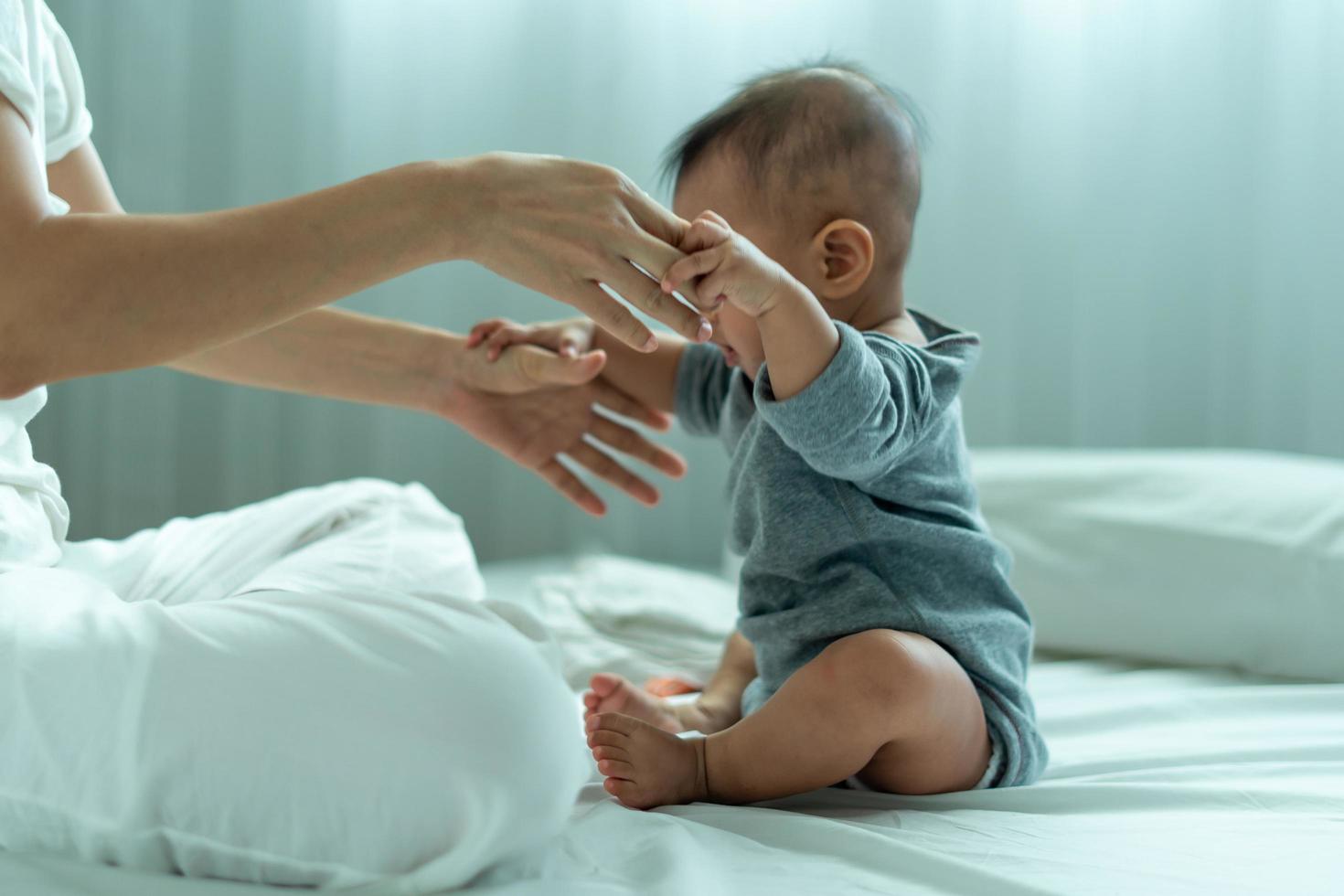 spädbarn asiatiska. ett asiatisk bebis litar på hans fars hand till stå upp. far och son utgifterna tid tillsammans foto