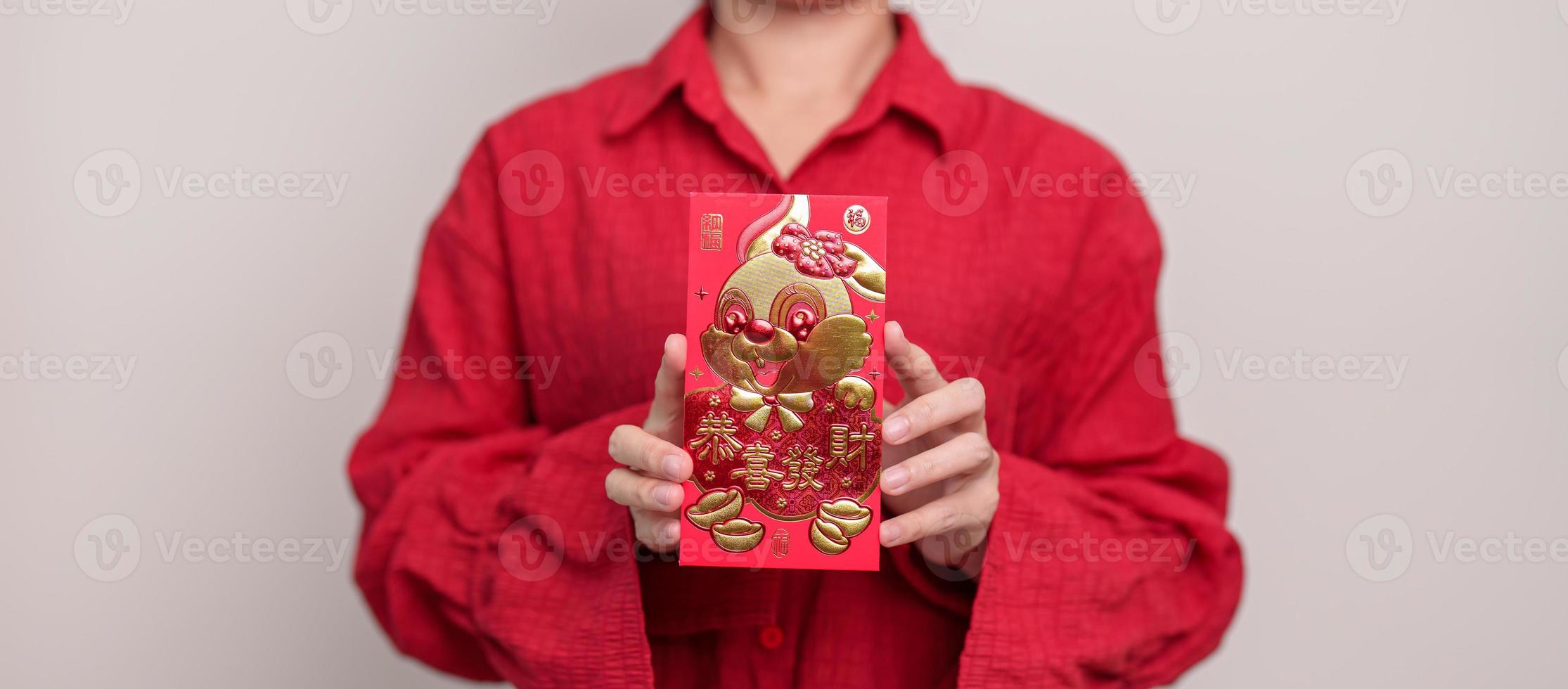 kvinna innehav kinesisk röd kuvert med gyllene kanin och välsignelse ord, pengar gåva för Lycklig lunar ny år Semester. kinesisk mening betyder lycka, friska, tur- och rik foto