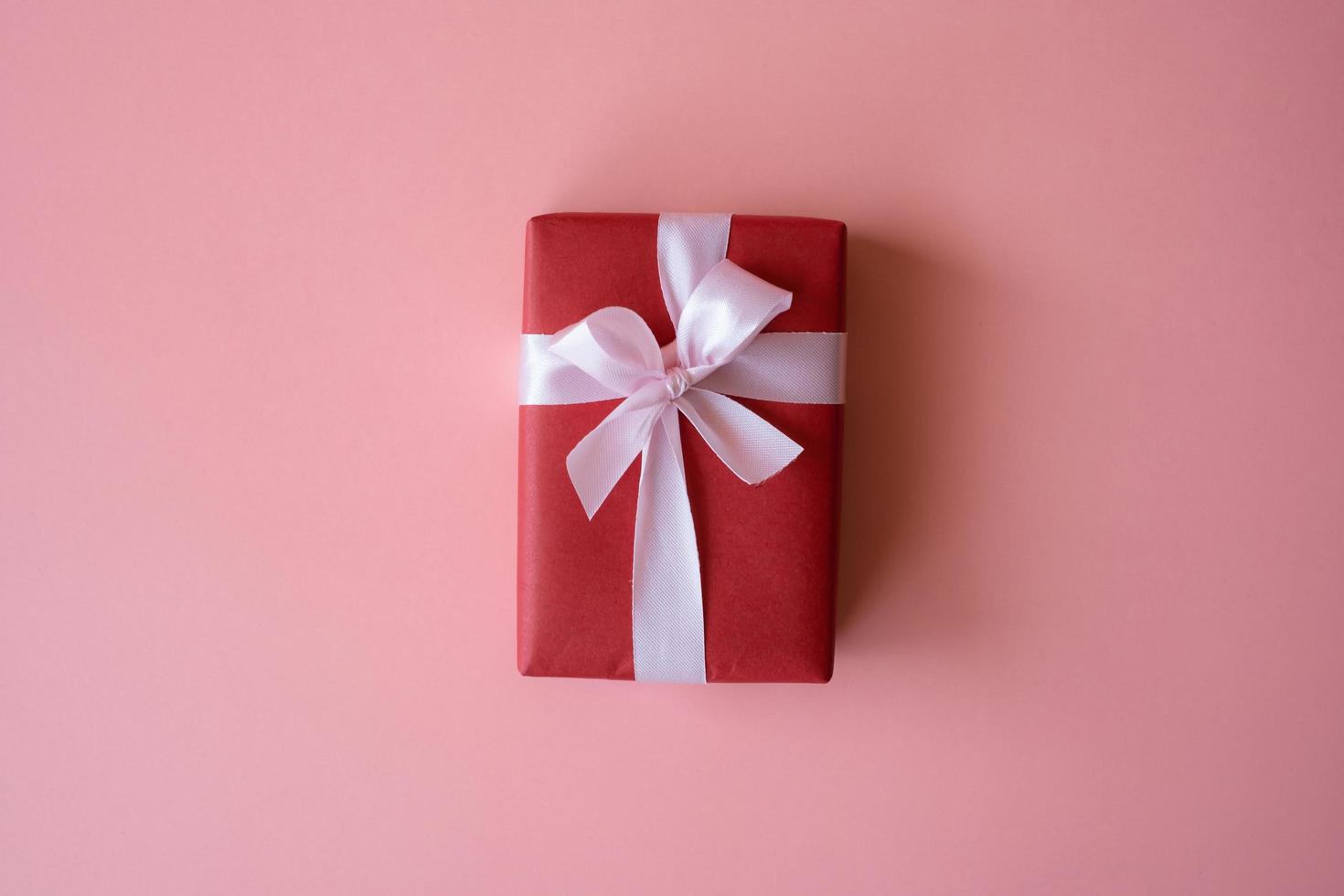 röd presentförpackning med band isolerad på rosa bakgrund för att ge i semester med kopia utrymme för text. helgdagar, nuvarande, ger koncept. nyårsdagen, juldagen, kinesiska nyårsdagen, födelsedag. foto