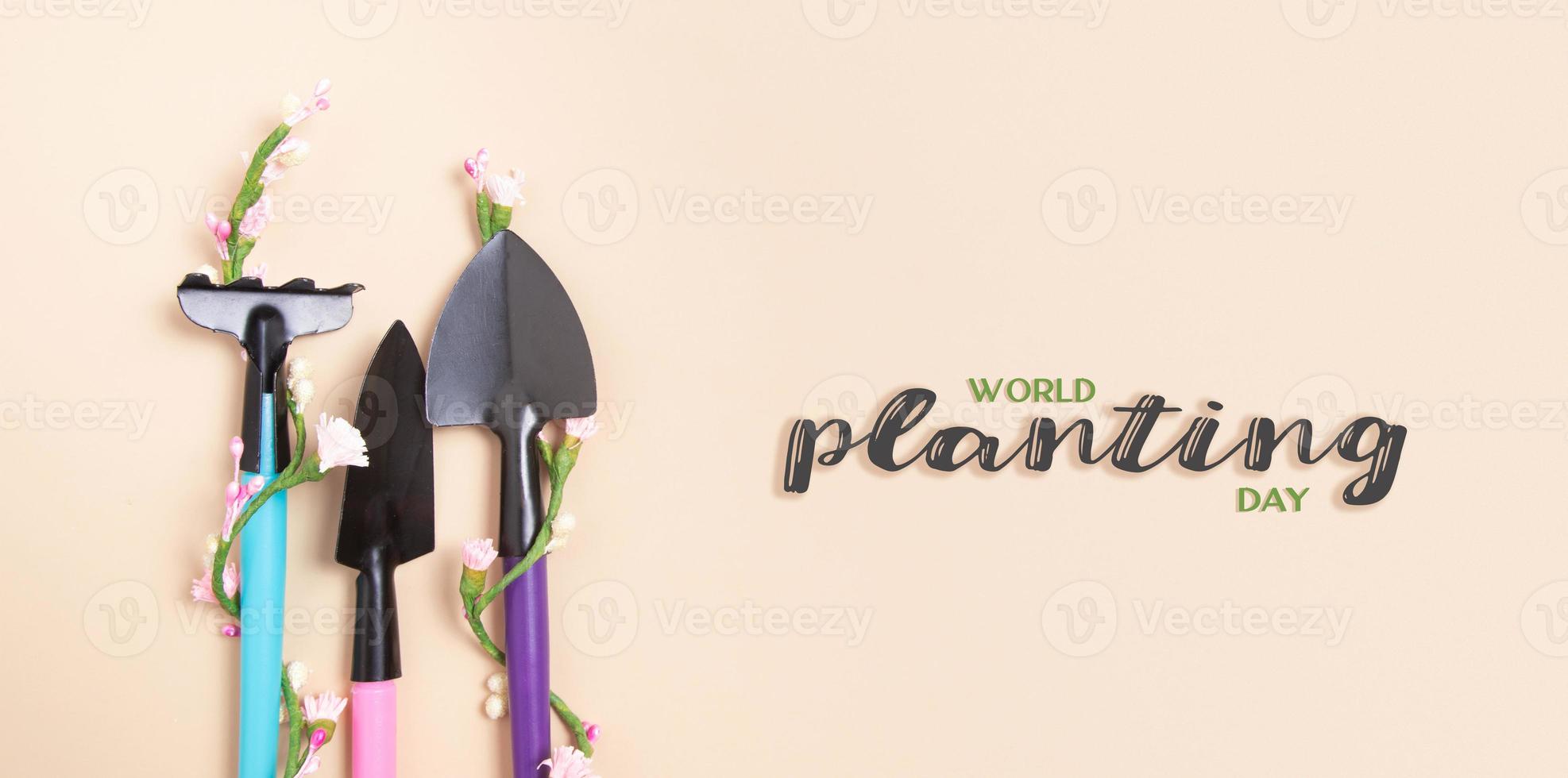 värld plantering dag text med spader och krattor för trädgårdsarbete. platt lägga. baner foto
