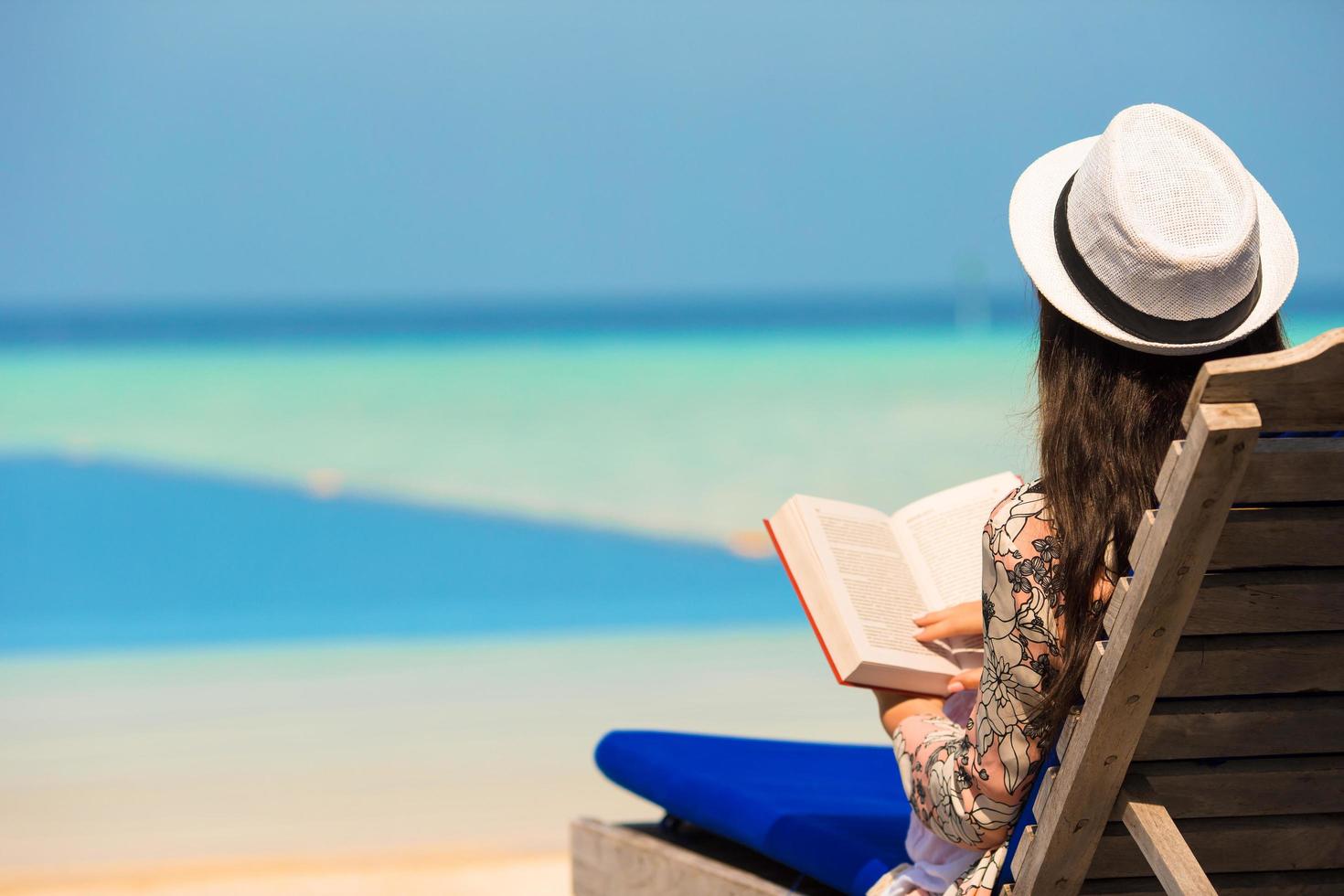 kvinna som läser en bok nära en pool foto