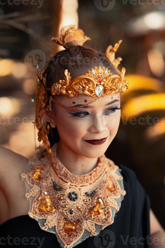 skön stam kvinna bär en guld drottning krona medan bär en svart kostym foto