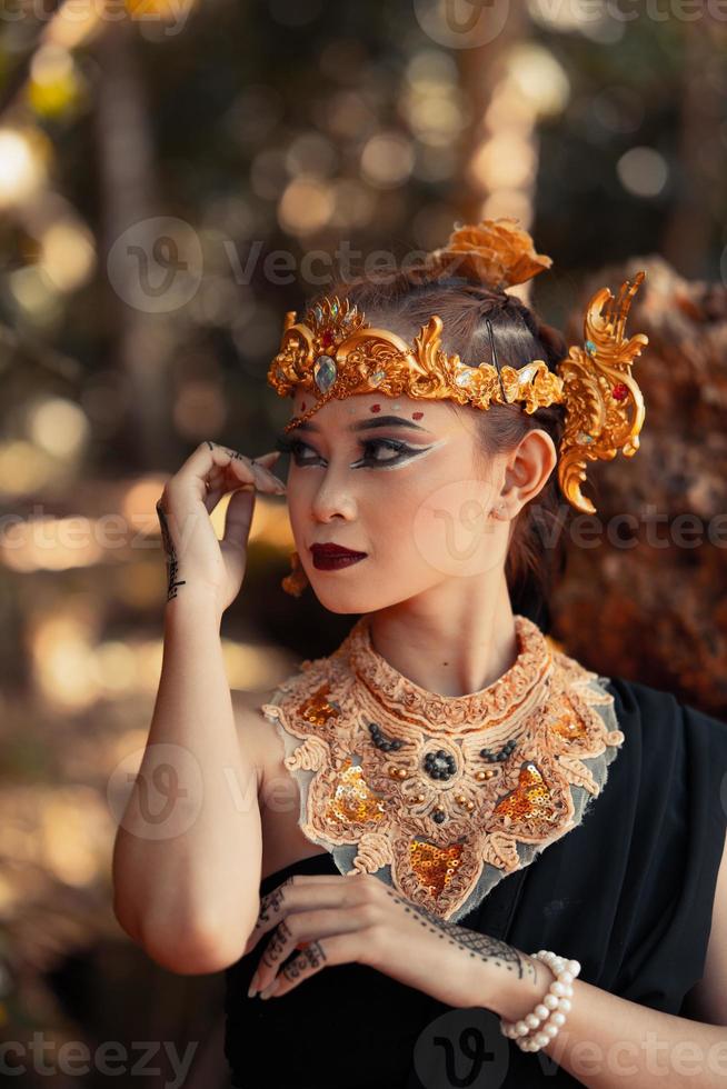stam- drottning i smink medan bär en guld krona och guld halsband med de svart klänning foto